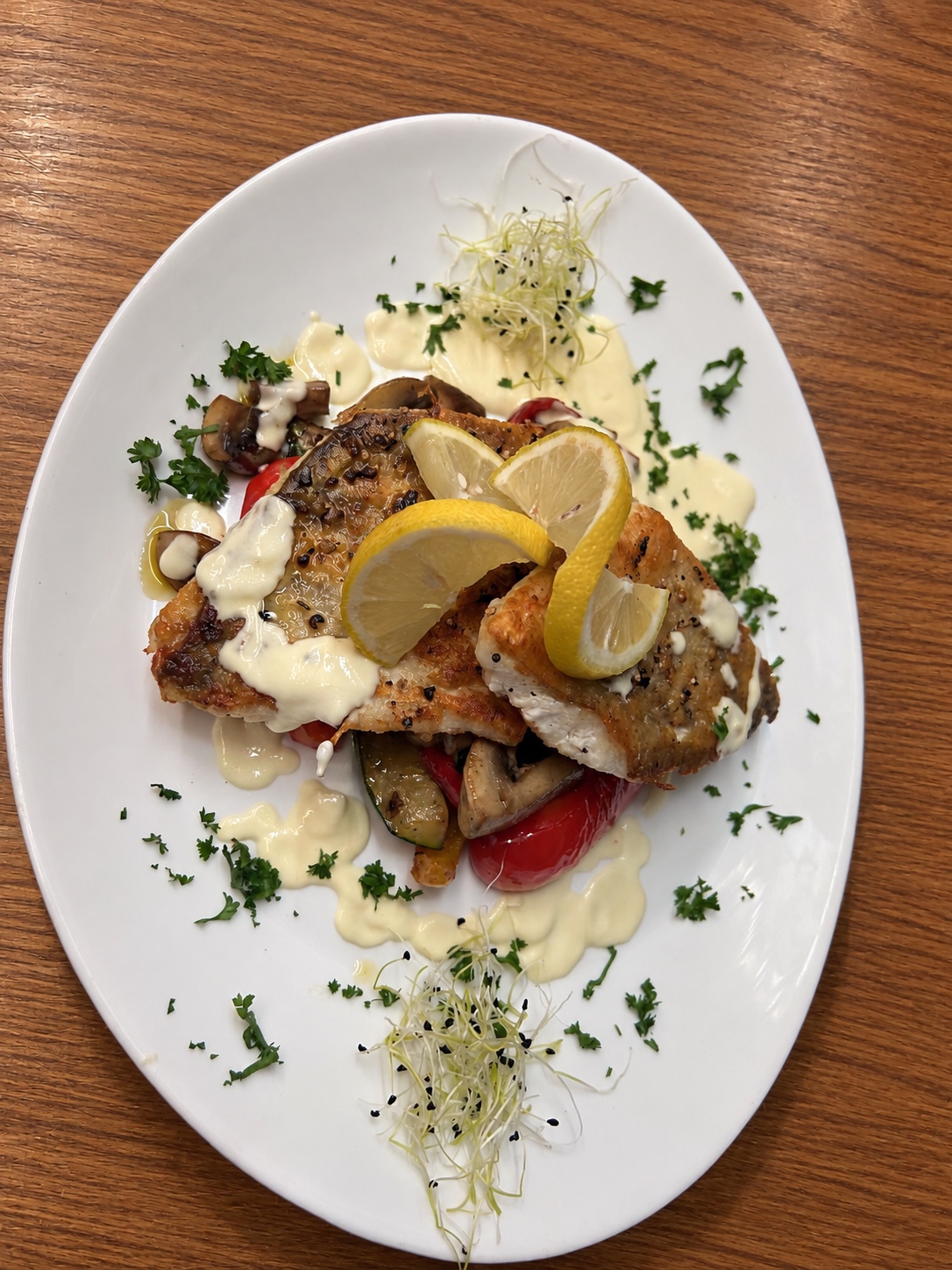 Zanderfilet auf weißem Teller mit Gemüse und Zitrone